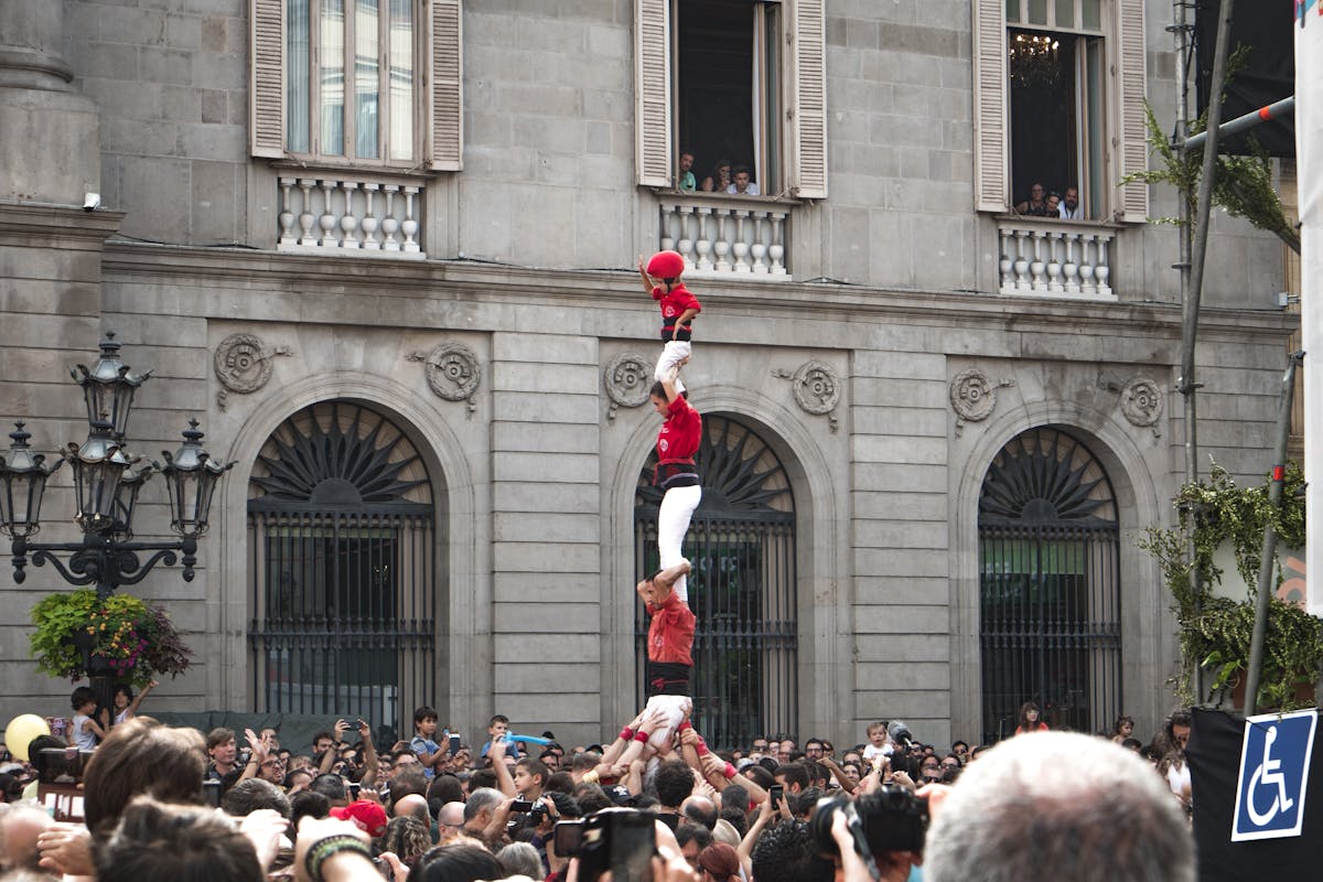 Castellers building a human tower during a Barcelona festival with crowd watching below
