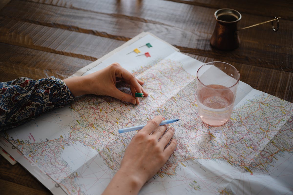 Travel planning flat lay with a Barcelona map, notebook, and camera on a wooden table