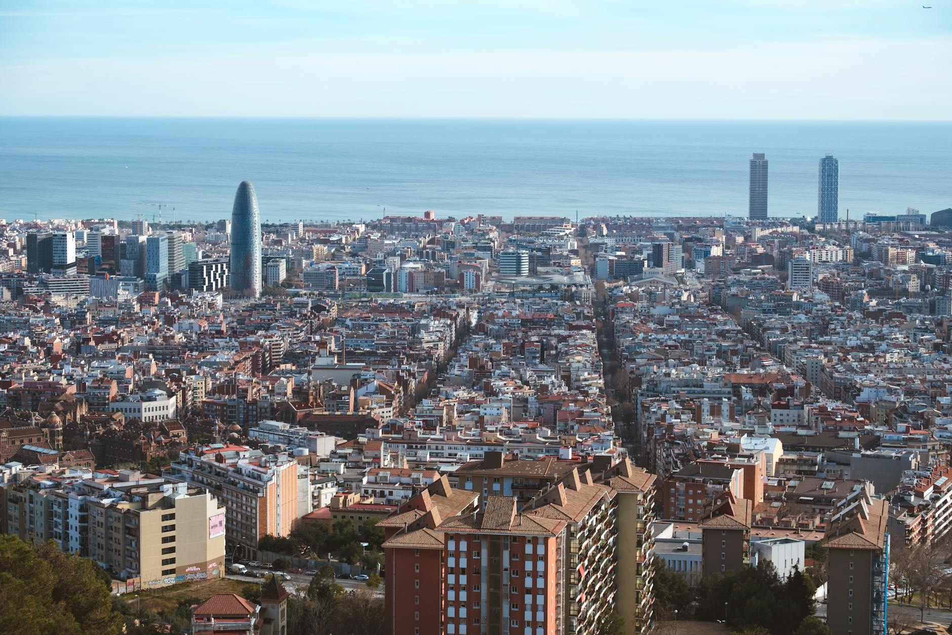 Aerial panoramic view of Barcelona's districts showing the grid layout of Eixample and the coastline