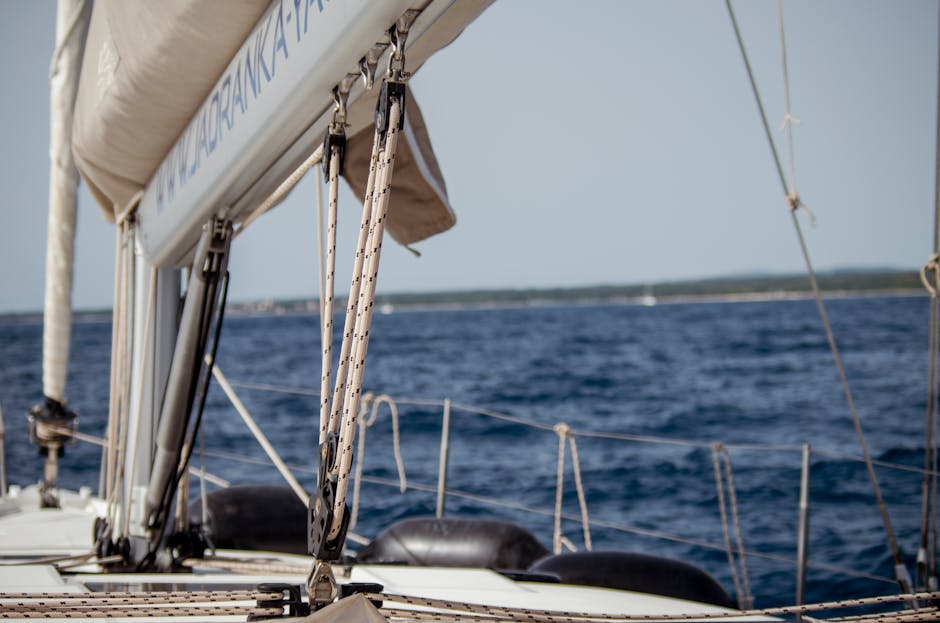 A sailboat with white sails on calm Mediterranean water near Barcelona's coast