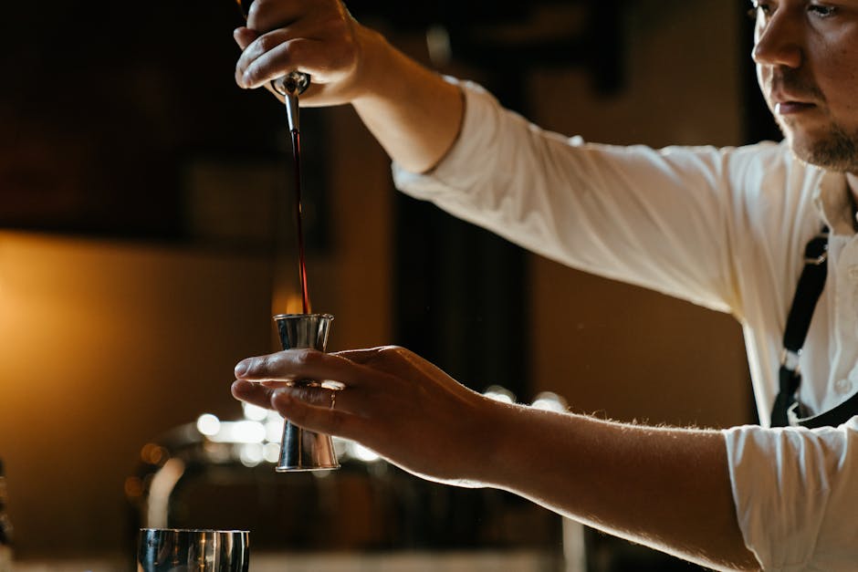 A bartender preparing a cocktail in a stylish Barcelona bar with low warm lighting