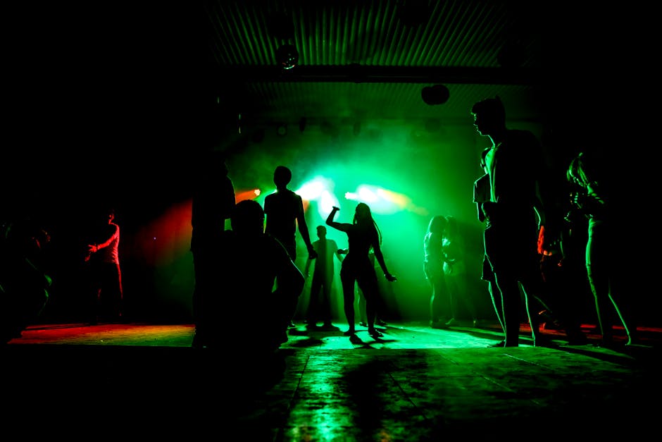 Crowded Barcelona nightclub dancefloor with pulsing lights and a DJ booth at the back