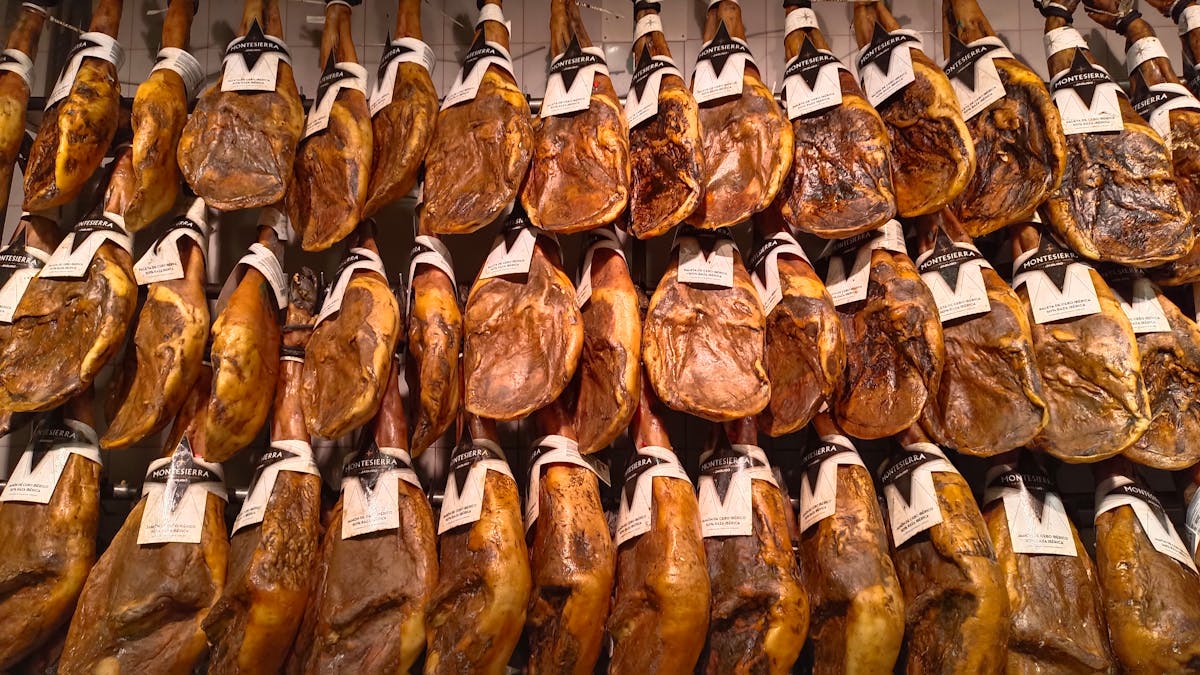 Thin slices of Iberian jamon draped over a wooden board with bread and olive oil