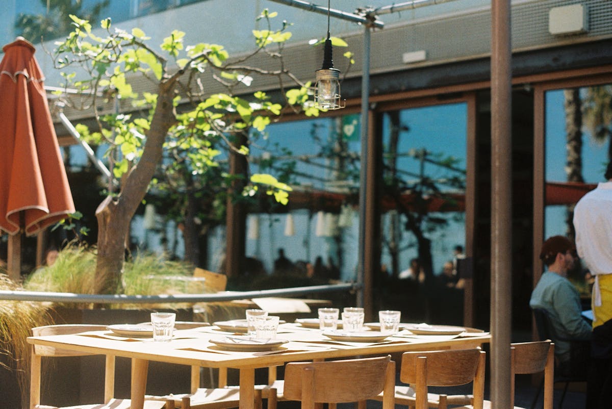 Outdoor terrace of a tapas bar in Barcelona with diners enjoying small plates and wine in the evening sun