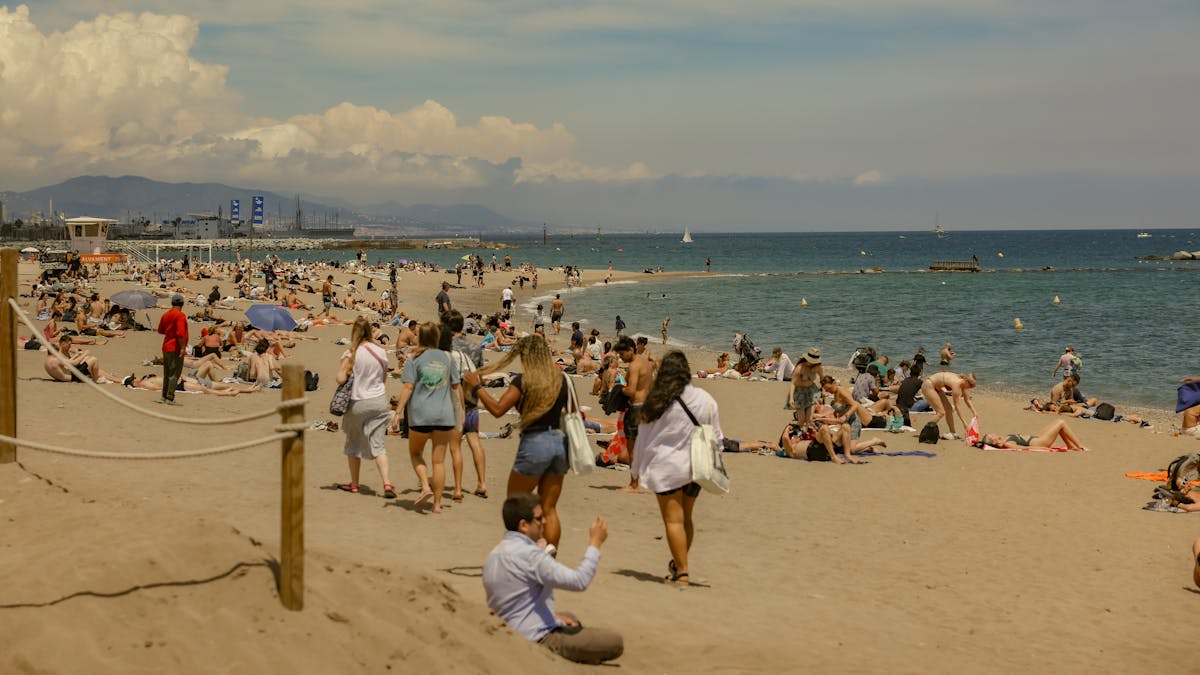 Crowded Barceloneta beach on a hot summer day with swimmers and sunbathers