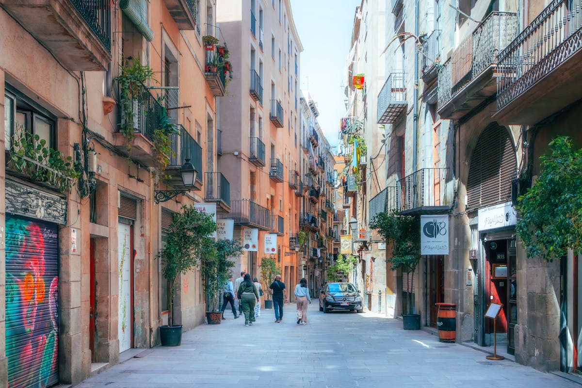 Peaceful Barcelona street in the Gothic Quarter with narrow alleyway, historic architecture, and walking tourists exploring the neighborhood