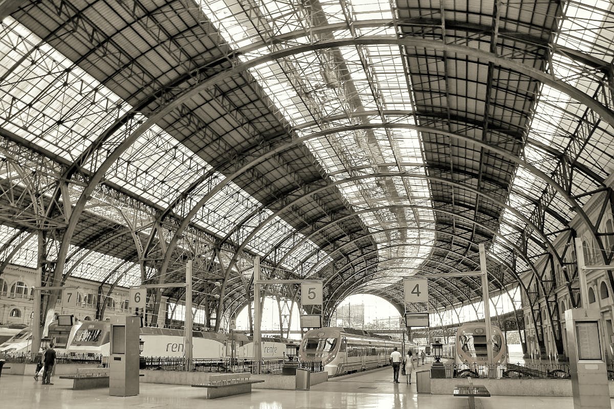 Barcelona Sants train station main hall with modern architecture, ticket counters, and travelers with luggage