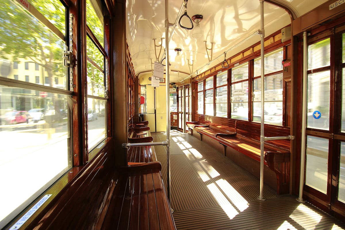 Historic blue tram car on tracks in Barcelona's Ronda district with period architecture and passengers boarding