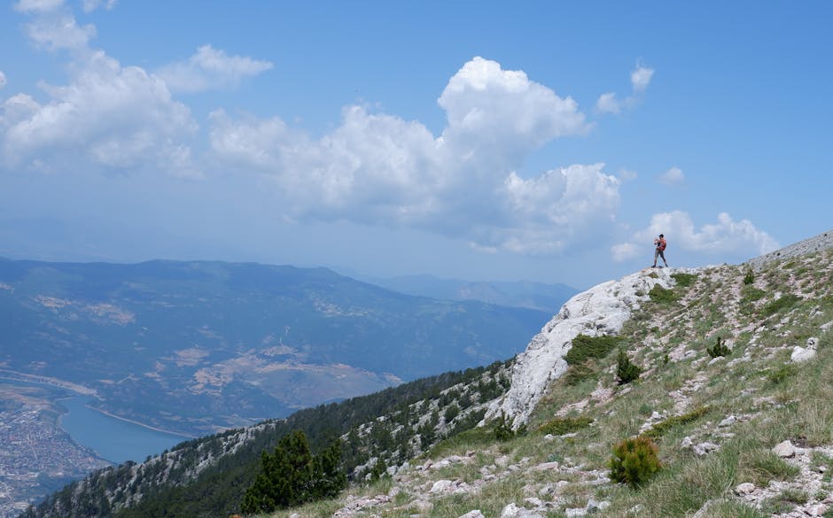 A hiker on the Sant Jeroni summit trail at Montserrat with the Catalan plain visible below