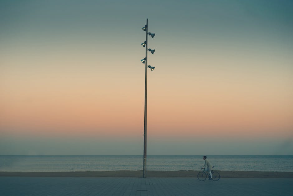 A cyclist riding along the Passeig Maritim boardwalk in Barcelona with the Mediterranean visible