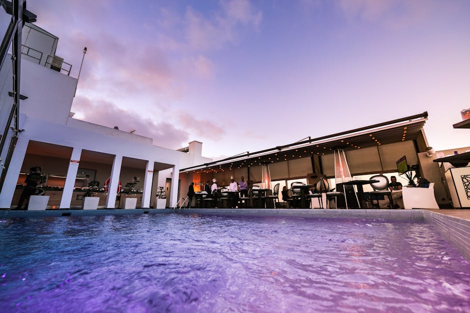A rooftop pool in Barcelona at sunset with cocktail glasses on the edge and city skyline behind