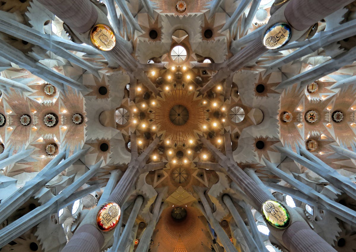 Interior of the Sagrada Familia showing tree-like columns branching toward the ceiling with coloured light streaming in