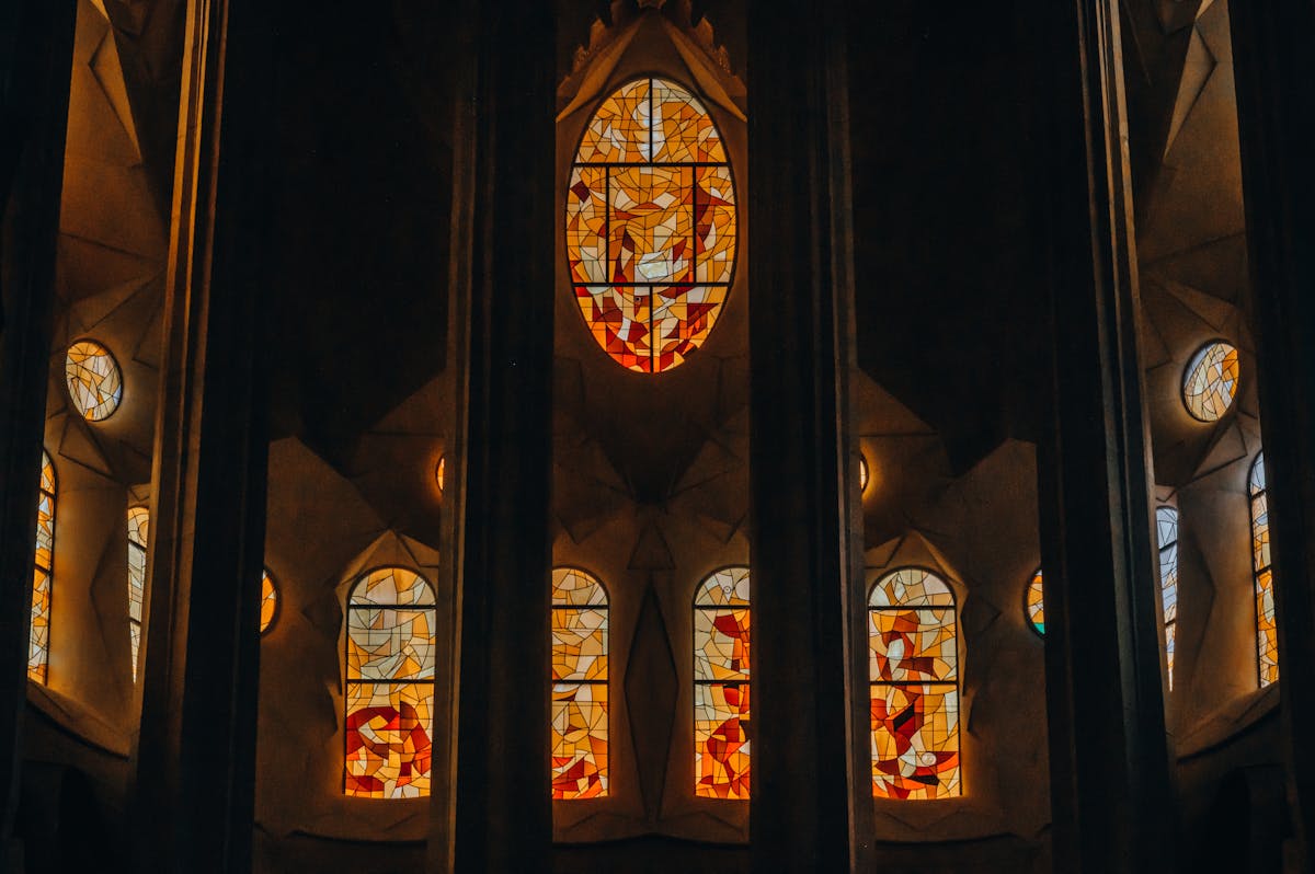 Stained glass windows inside the Sagrada Familia casting vibrant rainbow light across the stone columns and floor