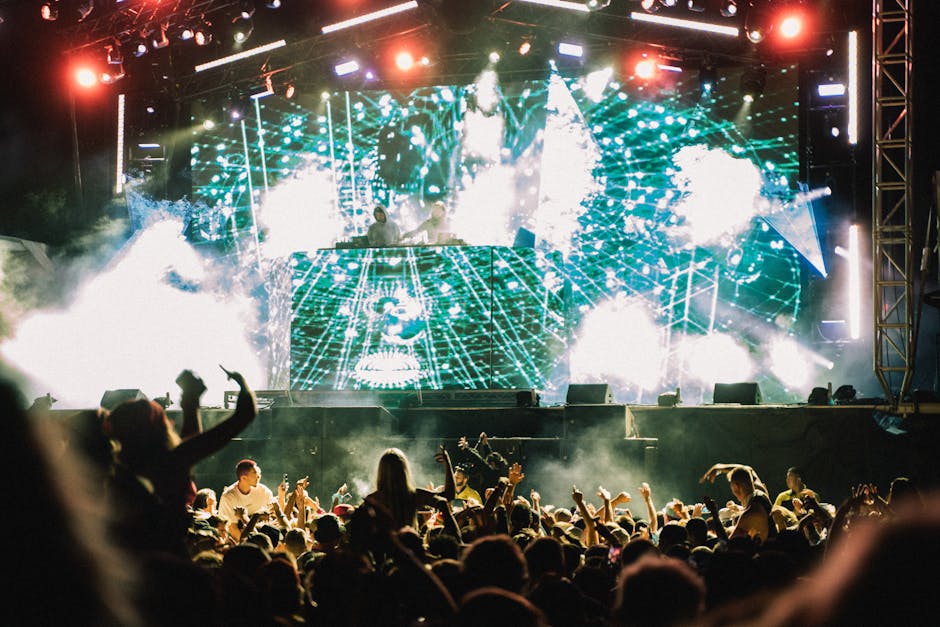 An electronic music festival crowd with light shows and DJ stage