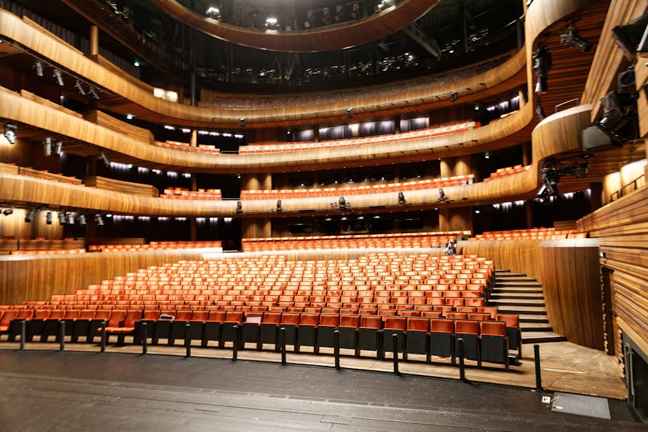 The view from theatre seats facing a stage with red curtains
