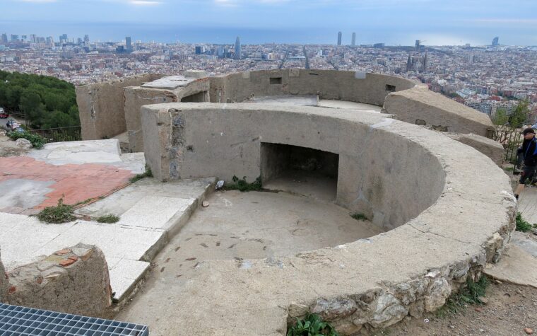 A circular concrete gun emplacement on the Turo de la Rovira with the Barcelona skyline, the Sagrada Familia and the sea beyond