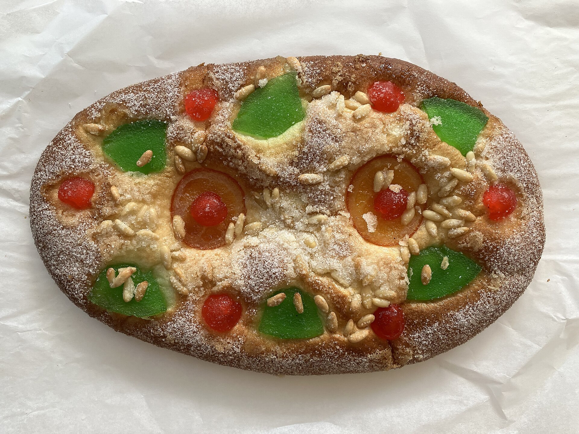 A coca de Sant Joan, a flat sweet pastry topped with candied cherries, candied fruit, pine nuts and sugar