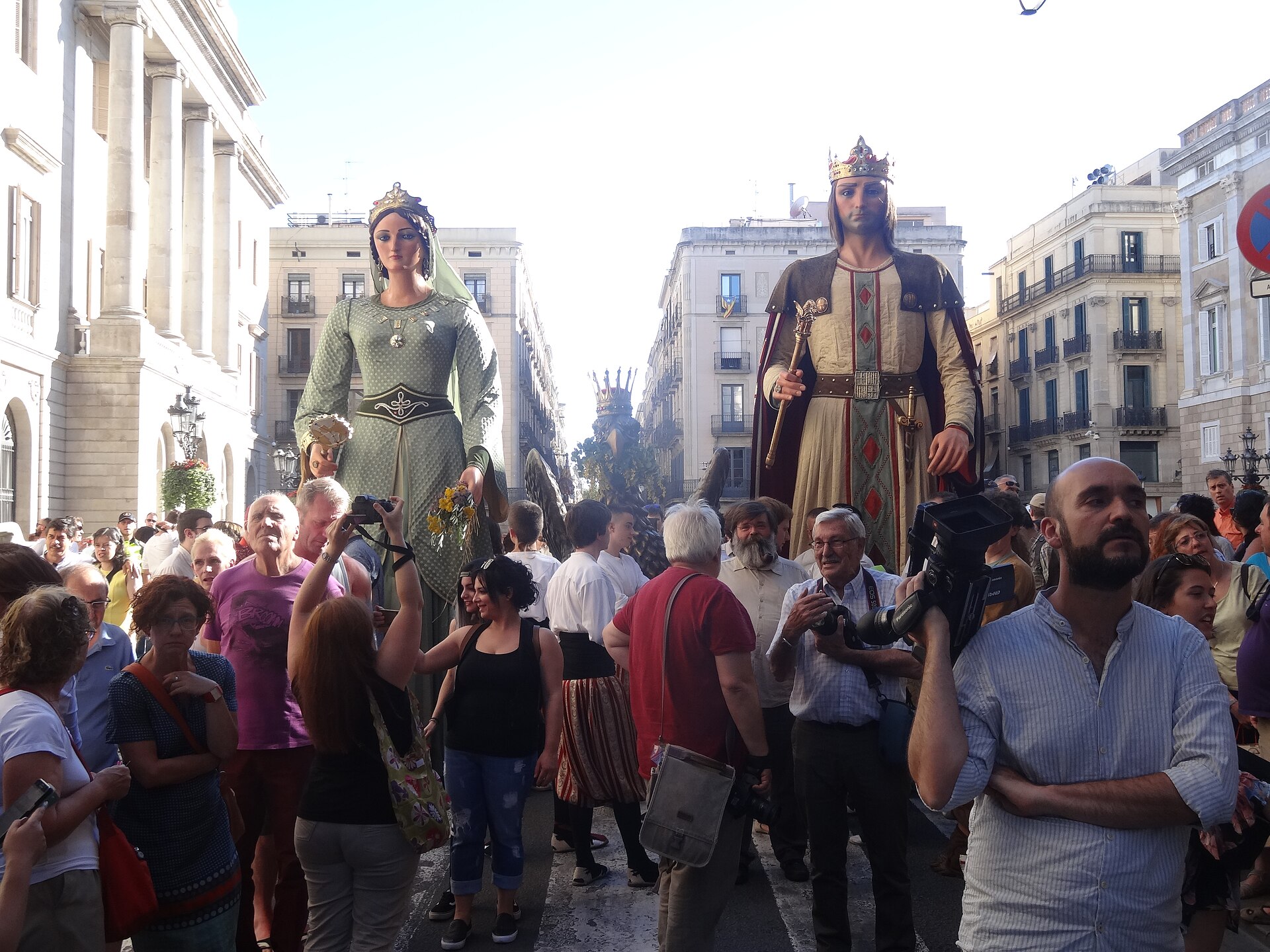 Barcelona's giant figures of a king and queen in Placa de Sant Jaume surrounded by crowds at the arrival of the Canigo Flame
