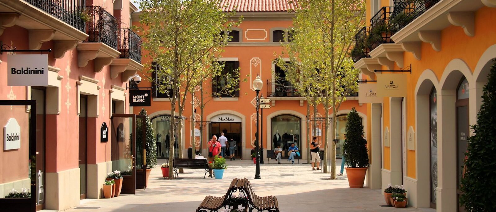 A quiet square at La Roca Village outlet with pastel buildings and boutique signs