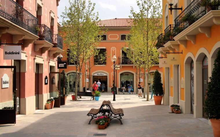 A quiet square at La Roca Village outlet with pastel buildings and boutique signs