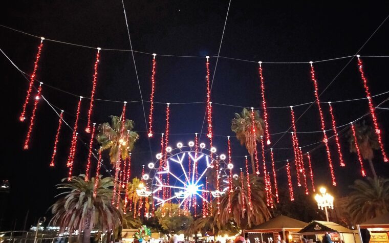 Strings of red Christmas lights hung between palm trees on the Moll de la Fusta, with an illuminated Ferris wheel and crowds below