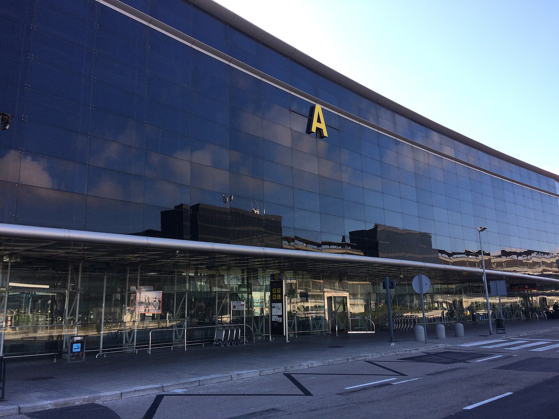 The glass facade of Terminal 2A at Barcelona-El Prat airport, with a large yellow letter A