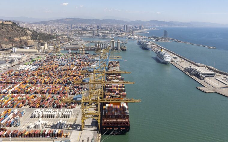 Aerial view of Barcelona's port, with the container terminal on the left and cruise ships berthed along the Moll Adossat on the right, the city and Montjuic behind