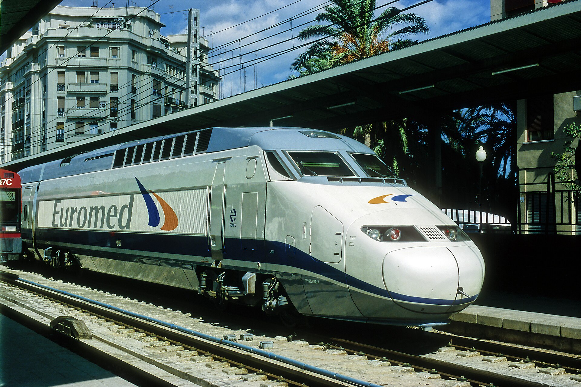 A first-generation Euromed high-speed train in white with blue and orange livery at a platform in Valencia's Nord station