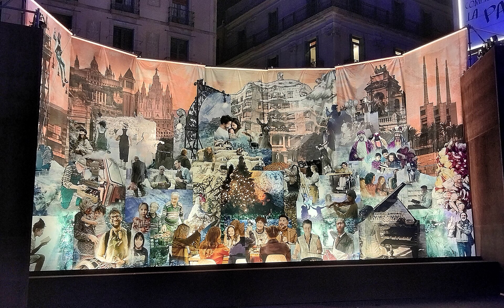 A large illuminated nativity collage in Placa de Sant Jaume, mixing Barcelona landmarks, families and the holy family