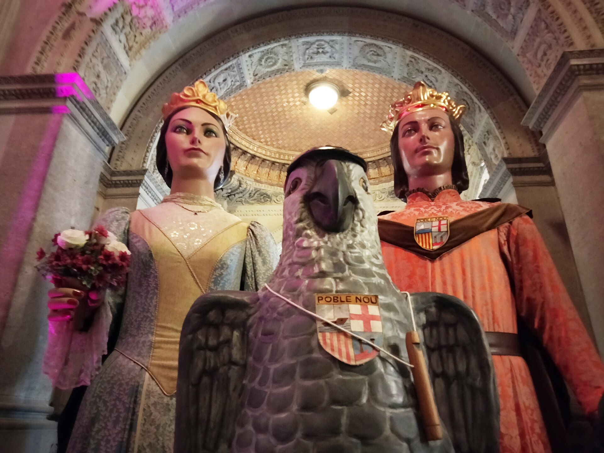 The giants of Poblenou, a crowned queen holding flowers and a crowned king, with a large parrot figure between them