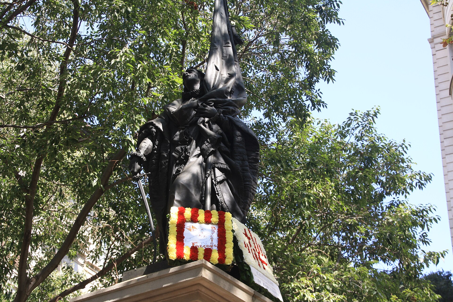The bronze statue of Rafael Casanova holding a flag, with wreaths in the red and yellow Catalan colours laid at its base